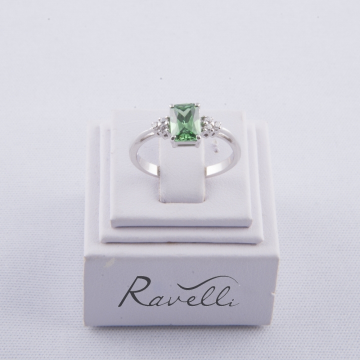 Anello in oro bianco 18 kt con smeraldo sintetico rettangolare incastonato a griffe e duraliti laterali taglio brillante.
